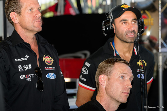David Reynolds watches the screen showing the Top 10 Shootout waiting for his turn.. Also watching is Stephen Grove (team owner) and David Cauchi (team principal).